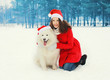 © rohappy - Woman with white Samoyed dog wearing a santa red hats in winter