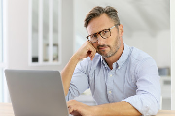 Handsome 40-year-old man at home using laptop