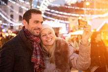 Young Attractive Couple In A Christmas Market Taking Selfie