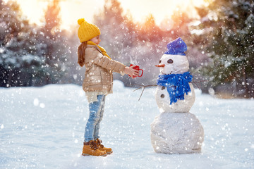 Poster - child girl plaing with a snowman