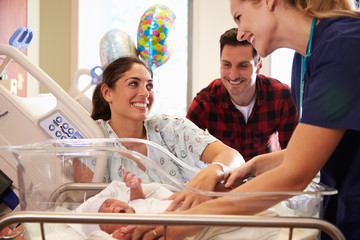 Family And Nurse With New Born Baby In Post Natal Department