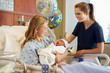 Teenage Girl With Nurse Holding Newborn Baby In Hospital