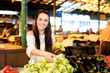 © veles_studio - Young smiling brunette woman at the market choosing a fresh white bell peppers
