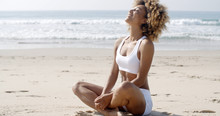 Woman Meditating On Beach In Lotus Position