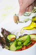 Aderezando con aceite de oliva virgen extra una ensalada mediterránea con hortalizas ecológicas y vegetales frescos.