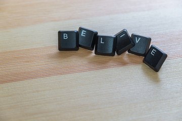 Leinwandbilder - Belive word keyboard on wooden floor