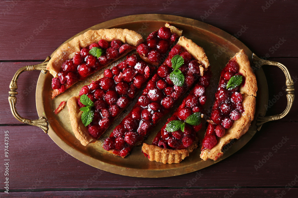 Tart with raspberries on tray, on wooden background