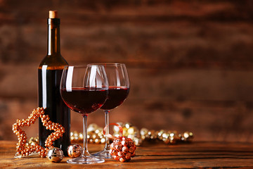 Red wine and Christmas ornaments on wooden table on wooden background