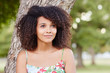 Beautiful mixed race woman smiling and daydreaming in a park
