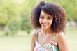 Beautiful woman with afro style hair smiling in a park