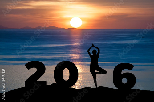 Fotografia Silhouette young woman play Yoga on the sea and 2016 years while celebrating new