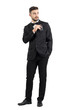 © sharplaninac - Relaxed cool handsome man in tuxedo with bow tie putting mobile phone in pocket looking away.  Full body length portrait isolated over white studio background.