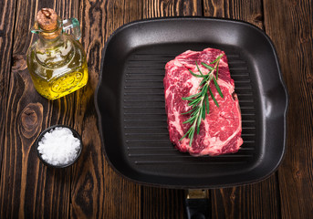 Wall Mural - Raw marbled meat steak Ribeye on grill pan on dark wooden background