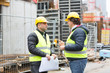 © cineberg - Workers with yellow safety jacket and hardhat talking at construction site reviewing plans