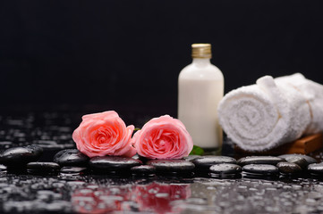 Two rose and towel with massage oil and therapy stones 