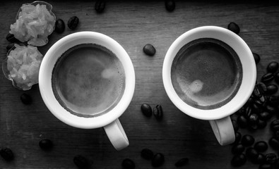 Two espresso coffees in small white cups,with a coffee bean rest