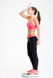 © Drobot Dean - Upset disappointed fitness girl standing on weighing scale