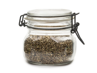 Wall Mural - Hemp seeds in a closed glass jar with lid on white background