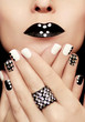 Multicolored manicure with white and black nail Polish decorated with rhinestones and a ring on his hand.