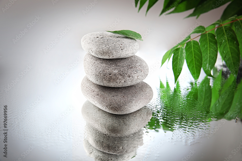 Spa stones and green branch on  grey background