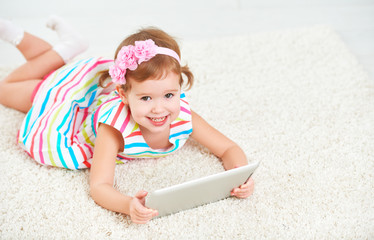 Fototapete - happy child little girl playing in tablet computer