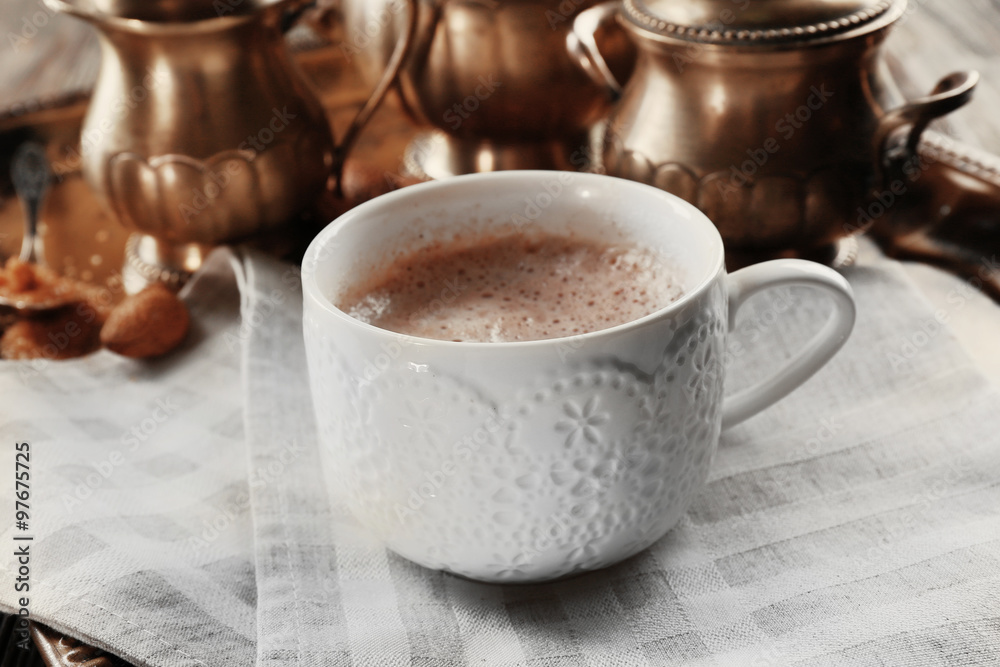 Cup of hot cacao on cotton serviette against silver service