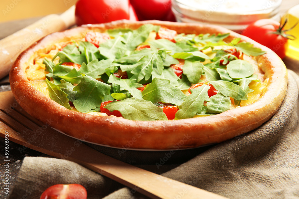 Pizza Margherita with arugula and kitchenware on wooden table
