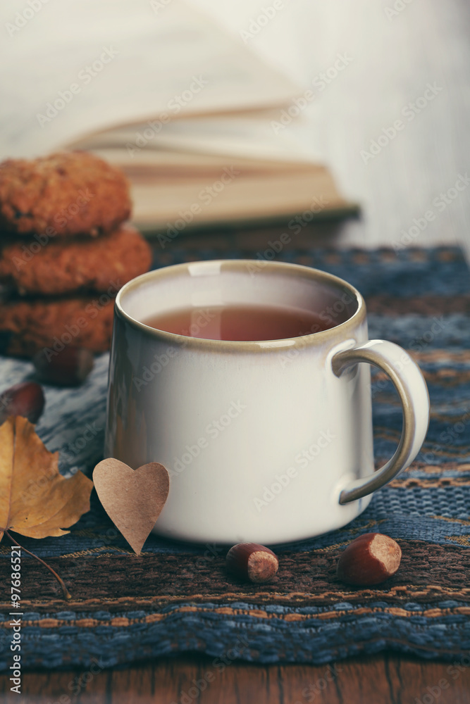 Cup of tea with autumn decor on wooden table.