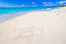 Happy New Year Written On Beach White Sand With Red Santa Hat