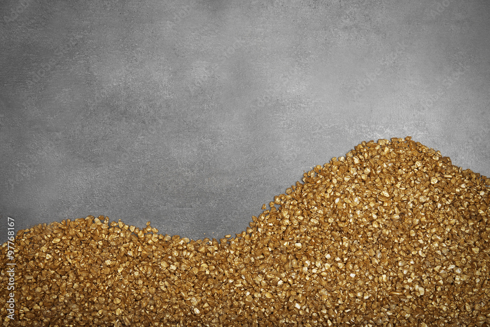 A corner of Gold nugget grains, on cement background