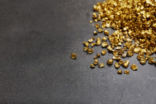 A Pile Of Gold Nugget Grains, On Cement Background