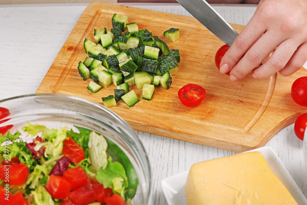 Female hands cutting vegetables for salad, at kitchen