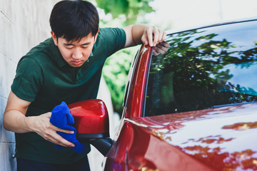 Young Asian man in uniform cleaning and washing a car in outdoor