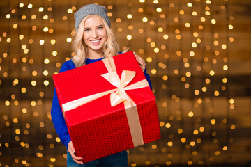 Poster - Woman holding gift box over holidays lights background