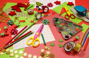 Arts and craft supplies for Christmas. Red and green color paper, pencils, different washi tapes, craft scissors, festive Xmas supplies for decoration.