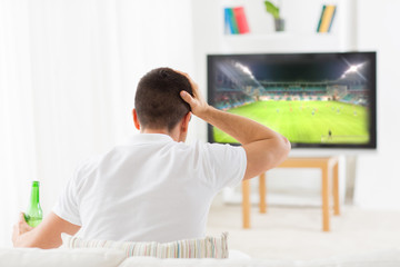 Wall Mural - man watching football and drinking beer at home