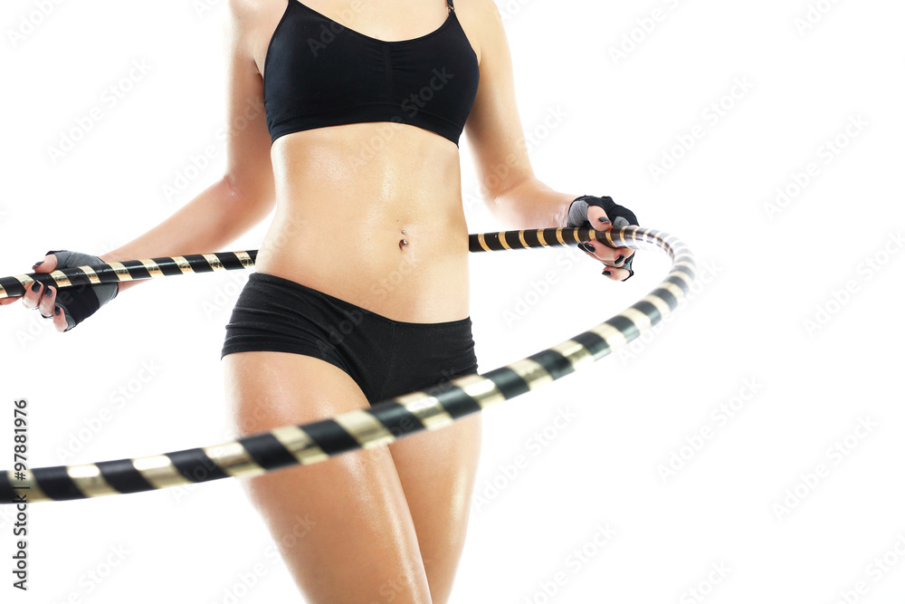 Kobieta trenuje mięśnie brzucha kręcąc kołem hula hop. - obrazy, fototapety, plakaty 