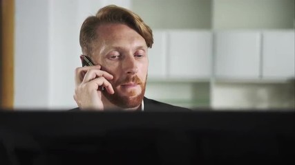 Poster - Red-haired man sitting at a computer and calling on the phone