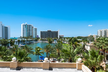 Luxury Resort Buildings At Sarasota Bay In Florida USA. Architectural Residential Condominiums For Holidays And Vacation With Palm Trees Against Blue Sky Background