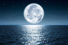 Full Moon Rising Over Empty Ocean At Night With Copy Space