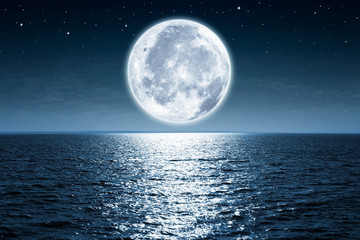 full moon rising over empty ocean at night with copy space