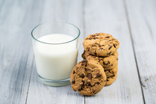 Glass With Milk And Chocolate Chip Cookies On A Wooden Backgroun