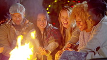  Happy Mixed Ethnicity Friends Socializing Outdoors In Front Of Fire Pit