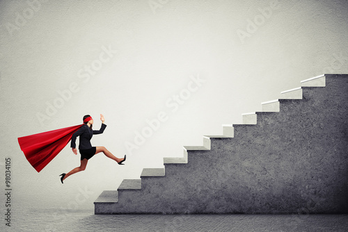 Fotografía superwoman in red cloar running up stairs