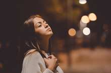 Young Thoughtful Brunette With Crossed Hand On Night Street Background