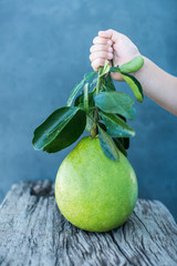 Wall Mural - Pomelo with green leaves on a wooden board