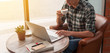 © stnazkul - Businessman using laptop with tablet and pen on wooden table in