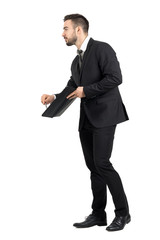 Side view of salesman showing signature space with pencil offering contract. Full body length portrait isolated over white studio background.