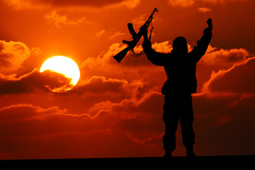 Silhouette of military soldier or officer with weapons at sunset. shot, holding gun, colorful sky, mountain, background