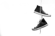 
Black And White Shot Of Pair Of Sneakers Hanging In Front Of A White Background
